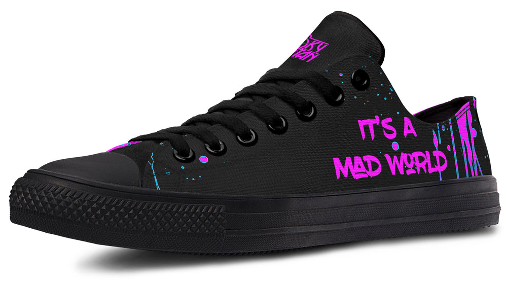 Black low-top sneakers featuring neon pink text reading “IT’S A MAD WORLD” on the outer side of the left shoe, set against a backdrop of chaotic pink splatter art. Matte black midsole, toe cap, and eyelets create a clean base that lets the pink design stand out. Cyber Cat design by Sky Titan Media, blending futuristic vibes with bold, music-infused streetwear energy.