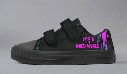 Black low-top sneakers for kids with bold cyber cat graphics, graffiti slogans, and a street-tough silhouette — now with easy Velcro straps for active little rebels.
The left shoe shows off pure punk: “It’s A Mad World” pops in pink across the side. Black straps and black toe box let the wild words take center stage.