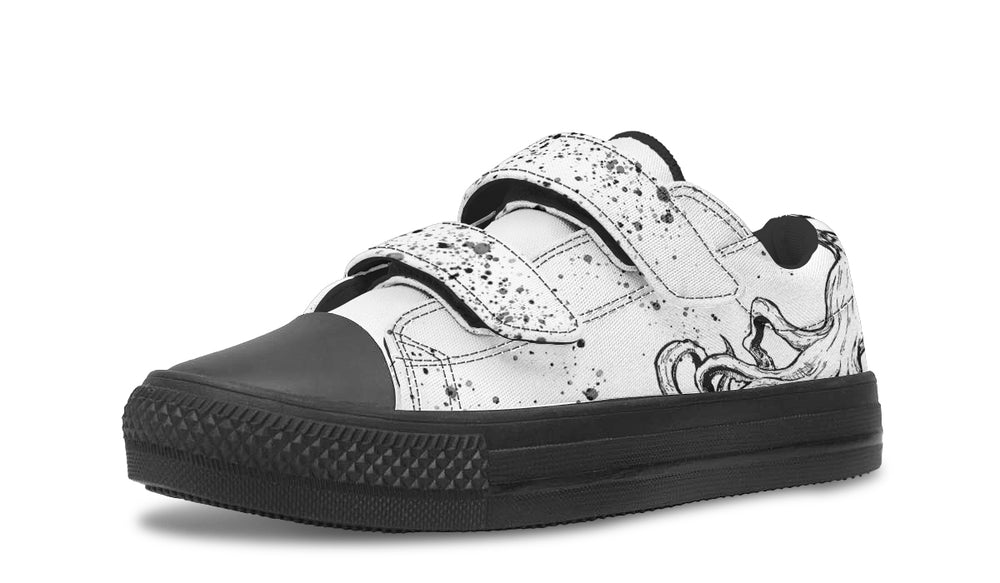Outer view of the white left kids’ sneaker featuring dynamic black ink splatter stretching across the canvas. The black sole, toe cap, and splatter-printed velcro straps add contrast and edge, turning playful chaos into wearable art. — Octopus Mismatched Edition by Sky Titan Media, designed for bold, creative kids who wear their individuality with pride.