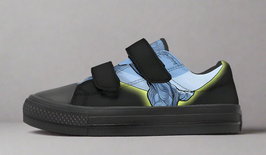 Kids’ black low-top sneaker with velcro straps featuring a blue comic-style illustration of Atlas lifting the sky on the outer panel. A visual symbol of strength, framed by functional streetwear structure. — Skybound design by Sky Titan Media, made for young dreamers with big imaginations and bold steps.