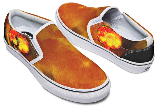 Black slip-on sneakers featuring asymmetrical artwork in fiery red-orange smoke across both shoes — the right shoe displays a bold Bomber Girl illustration on the outer side, while the left shoe features a stylized smoke explosion. White midsoles, inner quarters, and binding create high contrast and frame the design with sharp definition. — Bomber Girl design by Sky Titan Media, merging vintage attitude with edgy, music-fueled streetwear style.
