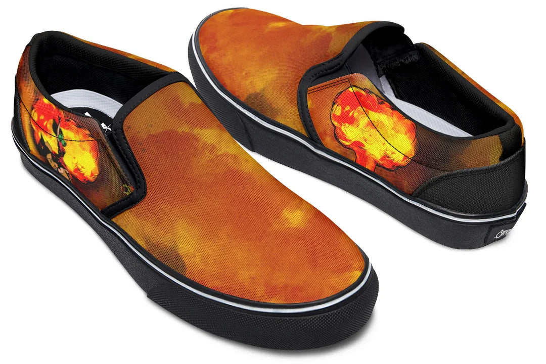 Black slip-on sneakers featuring asymmetrical artwork in fiery red-orange smoke across both shoes — the right shoe displays a bold Bomber Girl illustration on the outer side, while the left shoe features an abstract explosion blast. Inner sides of both shoes show the full smoke-textured canvas. — Bomber Girl design by Sky Titan Media, merging vintage attitude with edgy, music-fueled streetwear style.