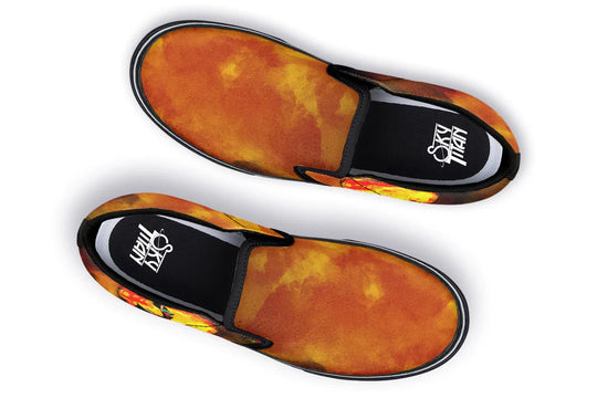 Black slip-on sneakers featuring a vivid orange-red smoke gradient flowing across the canvas uppers of both shoes. The black elastic gores and piping frame the design, while the Sky Titan logo is visible on the insole. No visible illustration from this angle, just bold color and clean silhouette. — Bomber Girl design by Sky Titan Media, merging vintage attitude with edgy, music-fueled streetwear style.