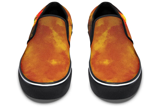 Black slip-on sneakers featuring a vivid orange-red smoke gradient flowing across the canvas uppers of both shoes. The black elastic gores and piping frame the design, while the Sky Titan logo is visible on the insole. No visible illustration from this angle, just bold color and clean silhouette. — Bomber Girl design by Sky Titan Media, merging vintage attitude with edgy, music-fueled streetwear style.