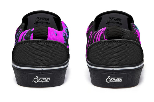 Black slip-on sneakers featuring asymmetrical cyber cat punk artwork and graffiti statements — the Cyber Cat Pink Edition by Sky Titan Media, fusing futuristic street rebellion with bold, music-charged expression.
Seen from behind, the silhouette remains sleek and structured: black canvas heels, clean seam lines, and a white midsole base bring subtle balance to the expressive chaos of the fronts and sides.