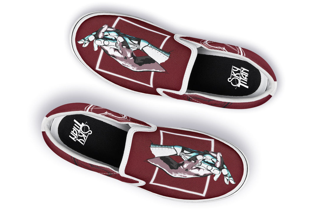Overhead view of the pair of red “July” slip-ons with white soles. The mirrored hand illustrations remain bold and central, while the enhanced stitching detail elevates both function and design for a cleaner streetwear aesthetic.
