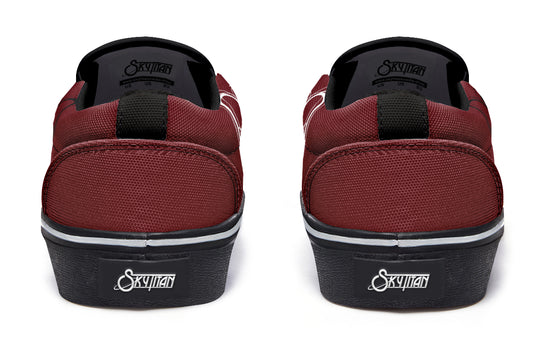 Back view of the red “July” slip-on sneakers. Black pull tabs rise from the heel, with the Sky Titan Media logo placed on a stitched black heel badge for distinct branding. Canvas texture and red paneling frame the design.