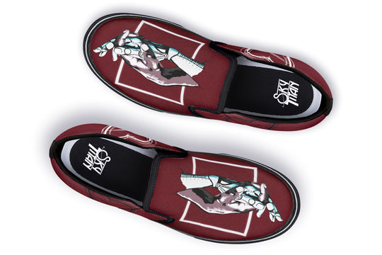 Top-down view of the “July” slip-on sneaker pair. Each shoe displays mirrored mechanical hand illustrations within a bold red canvas. The crisp black lining and visible Sky Titan Media insole branding complete the look.