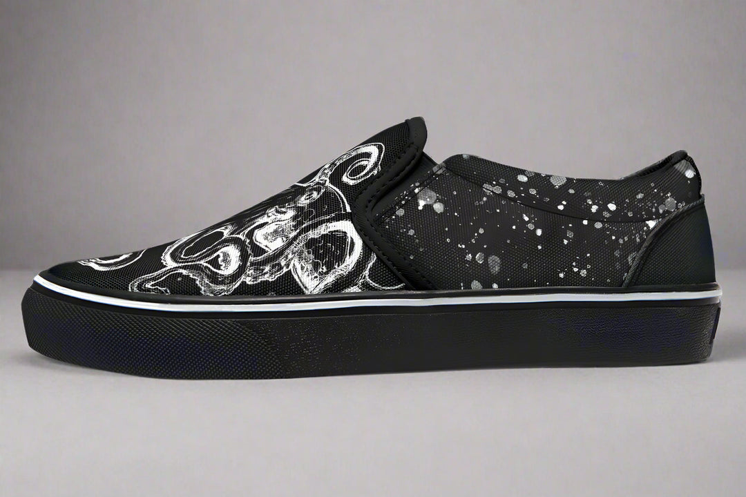Studio-lit side profile of Sky Titan Media’s Octopus Black Out Edition slip-on sneakers. The detailed white tentacle illustration wraps around the toe box and lateral panel, contrasted by subtle paint-splatter textures. White piping along the sole adds sharp contrast to the shadowy aesthetic.