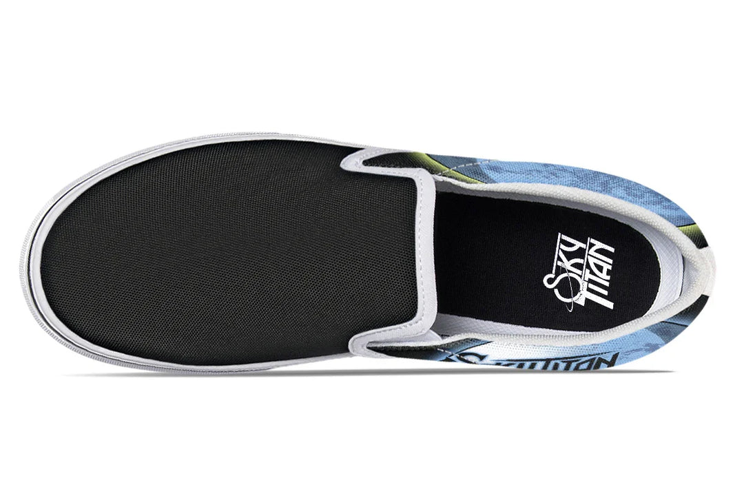 Top-down view of Skybound slip-ons in the white-detail variant. White elastic gores and midsoles contrast with the cosmic blue and yellow artwork flaring from the canvas sides. Sky Titan logos appear on both insoles. — Skybound design by Sky Titan Media, blending mythology-inspired visuals with streetwear rooted in independent music culture.