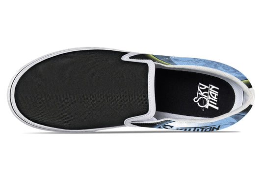Top-down view of Skybound slip-ons in the white-detail variant. White elastic gores and midsoles contrast with the cosmic blue and yellow artwork flaring from the canvas sides. Sky Titan logos appear on both insoles. — Skybound design by Sky Titan Media, blending mythology-inspired visuals with streetwear rooted in independent music culture.