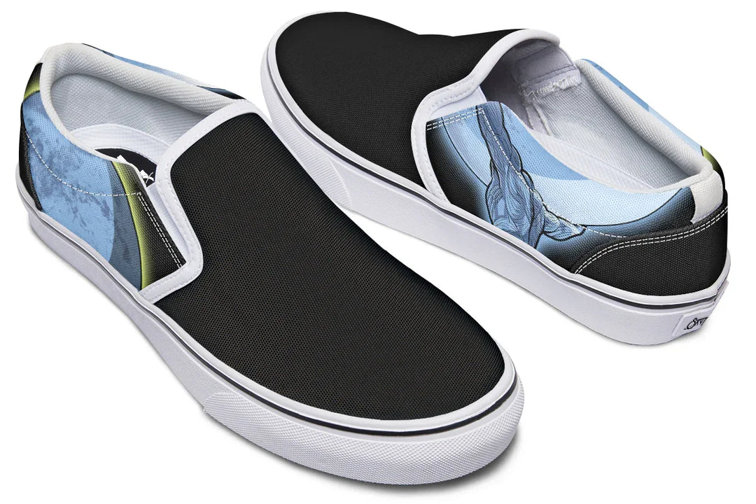 Black slip-on sneakers with white midsoles, inside quarters, and binding, featuring Sky Titan Media’s Skybound design. The left shoe displays a blue-toned Atlas across both outer and inner sides, lifting the sky toward the moon, while the right shoe features a glowing moon with a yellow halo stroke on the outer side, and a Sky Titan logo with the moon on the inner side. — Skybound design by Sky Titan Media, blending mythology-inspired visuals with streetwear rooted in independent music culture.