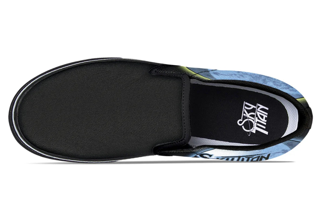 Top-down view of the Skybound slip-ons showing black elastic gores and a subtle interplay of blue and yellow moon graphics stretching out from both sides. Sky Titan logos are printed on the insoles. — Skybound design by Sky Titan Media, blending mythology-inspired visuals with streetwear rooted in independent music culture.