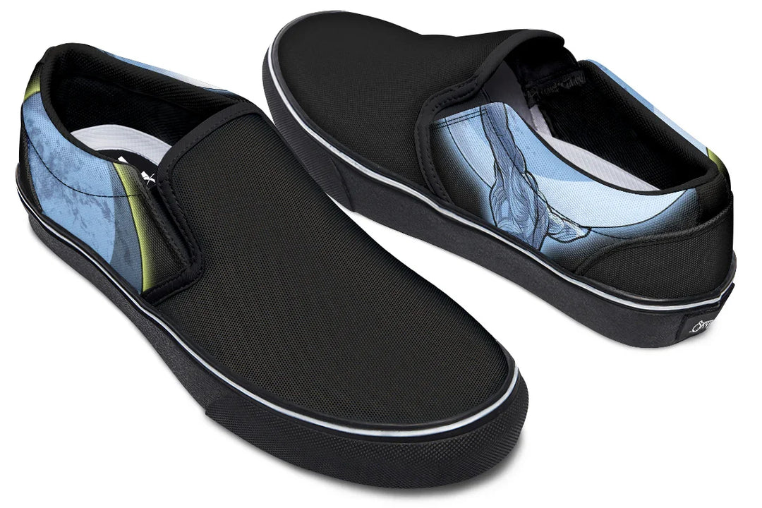 Black slip-on sneakers featuring Sky Titan Media’s Skybound design. The left shoe displays a blue-toned Atlas across both outer and inner sides, lifting the sky toward the moon, while the right shoe features a glowing moon with a yellow halo stroke on the outer side, and a Sky Titan logo with the moon on the inner side. A visual story of burden and balance told across both feet — Skybound design by Sky Titan Media, blending mythology-inspired visuals with streetwear rooted in independent music culture.