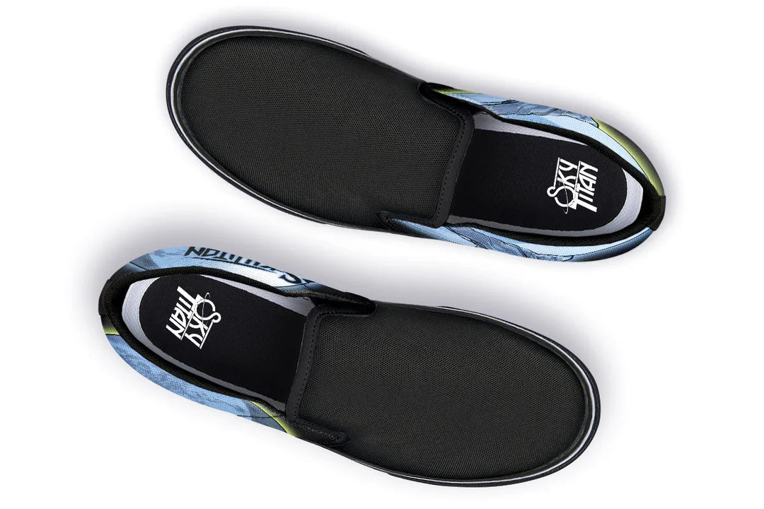 Top-down view of the Skybound slip-ons showing black elastic gores and a subtle interplay of blue and yellow moon graphics stretching out from both sides. Sky Titan logos are printed on the insoles. — Skybound design by Sky Titan Media, blending mythology-inspired visuals with streetwear rooted in independent music culture.